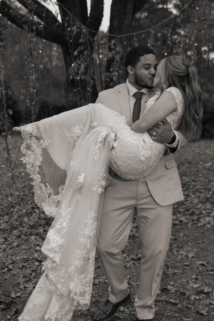 Groom carrying bride bridal style during couple's portraits in Covington, GA